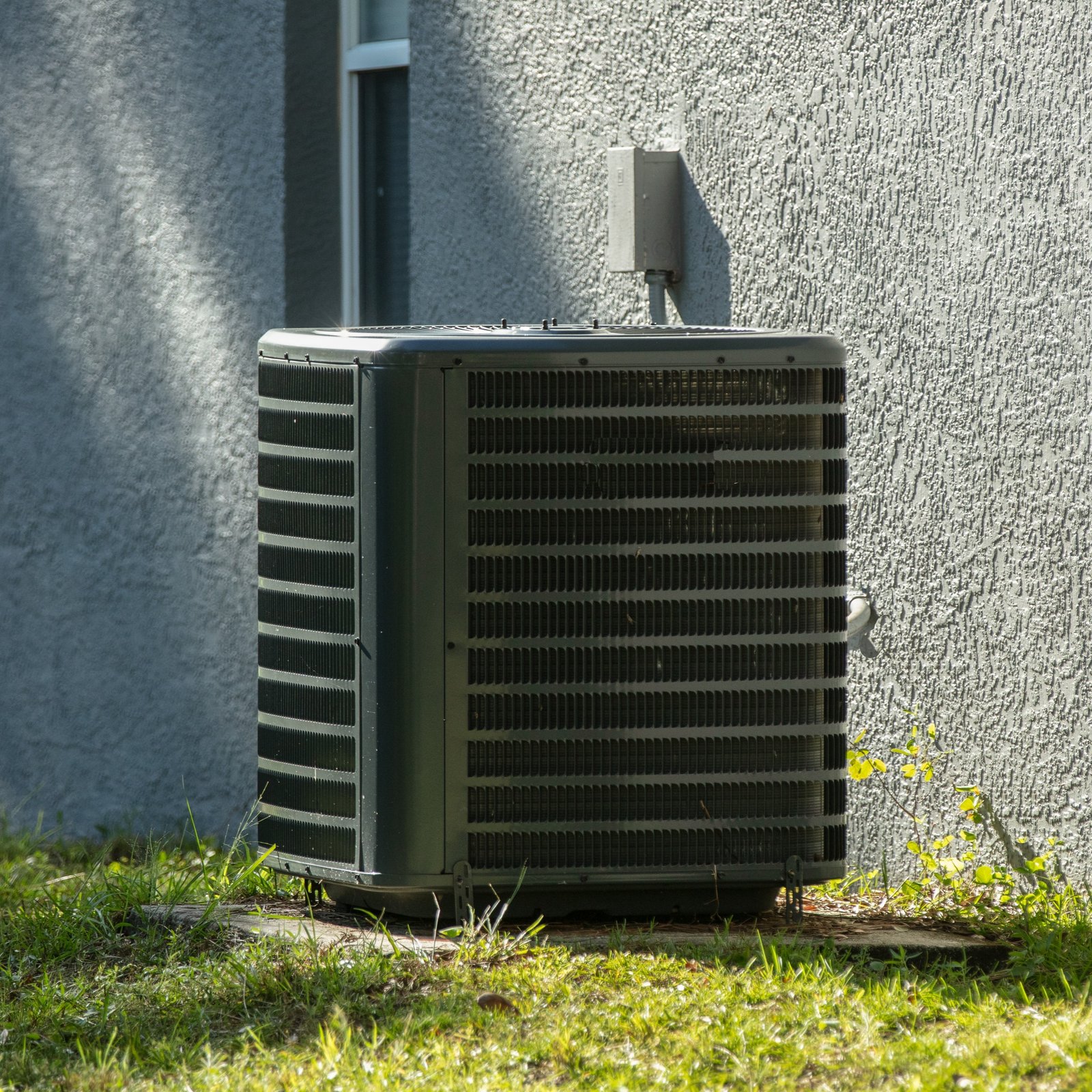 Smiling HVAC technician in a cap, inspecting an indoor air conditioning unit and checking its components